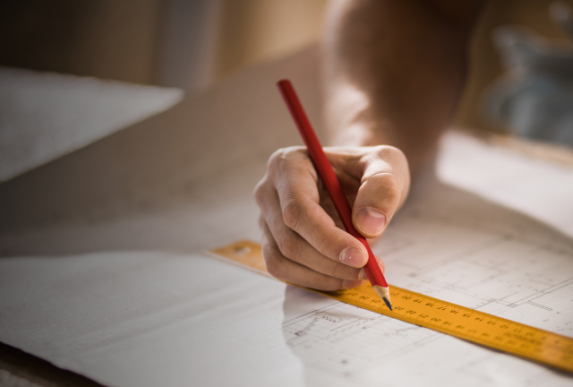 Hand drawing with a red pencil and ruler on a blueprint