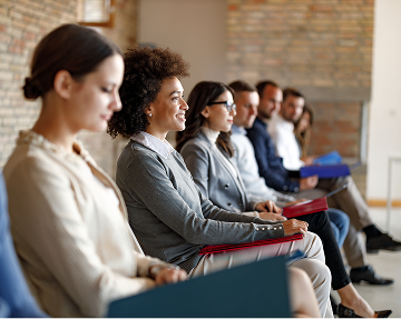 Professionals sitting in a meeting, focused on their laptops