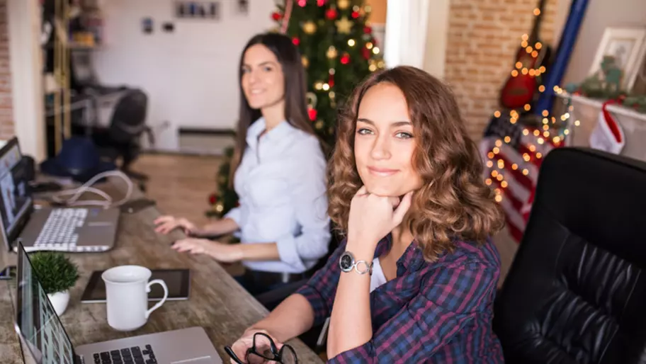 2 employees sit in front of holiday lights