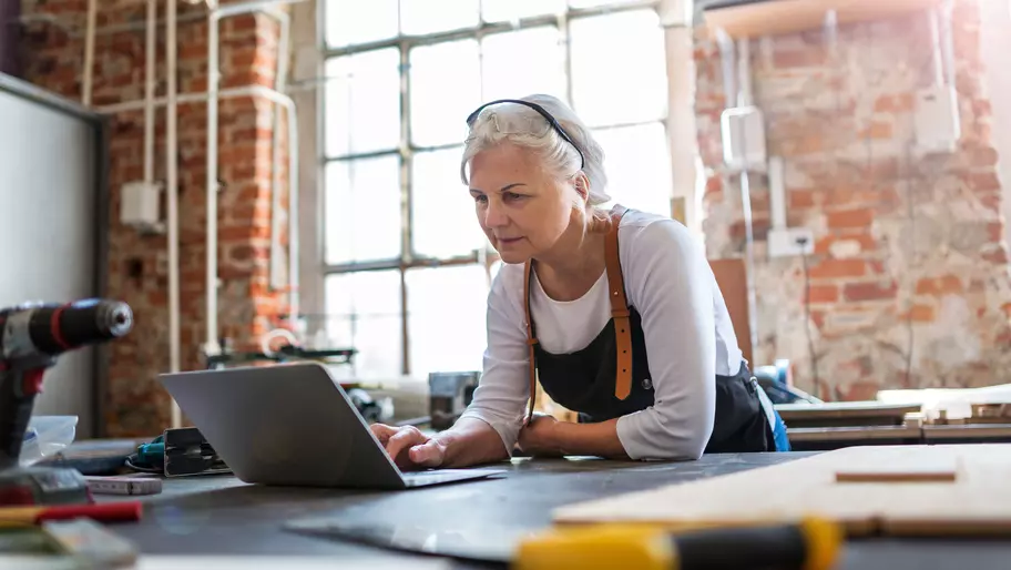 Older woman in workshop looking at laptop screen