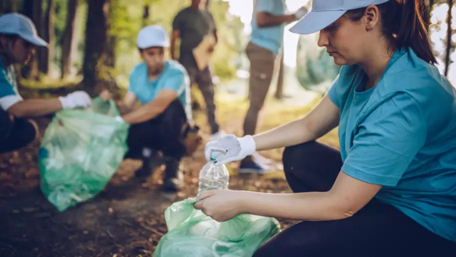 Men and women picking up trash in the woods and recycling it