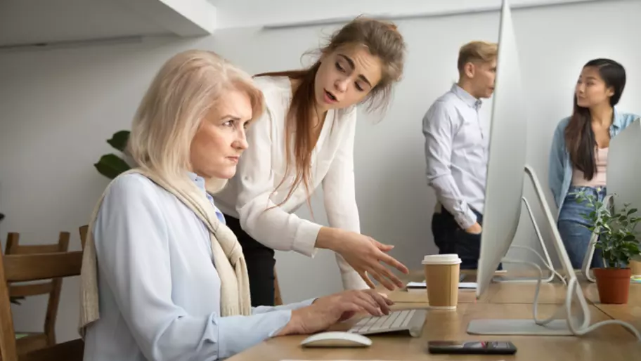 Young employee patronising older employee to illustrate ageism in the workplace