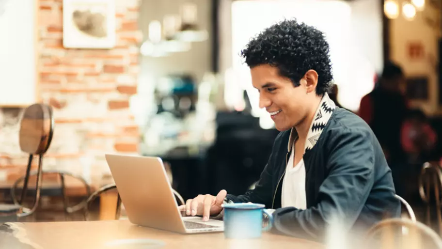 Young adult male on laptop in public place