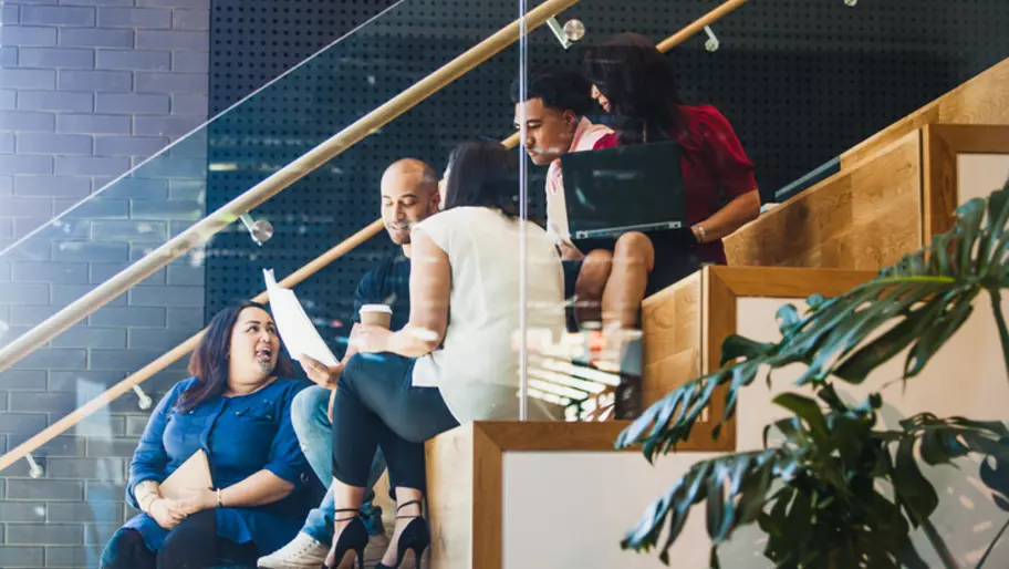 Colleagues on laptops sitting together on office stairs