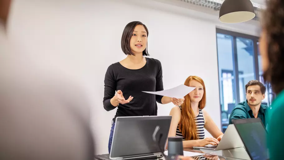 Woman standing in a meeting delivering a speech