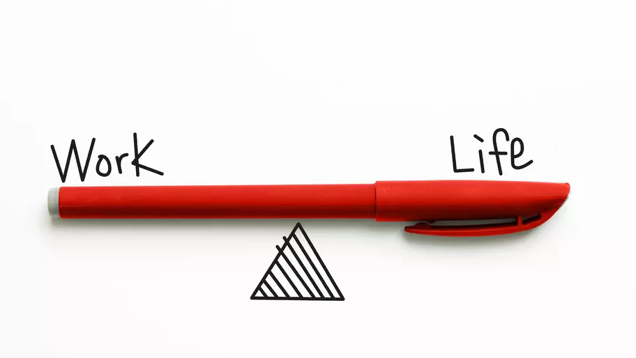 Red pen balancing on triangle with the words "work" and "life."