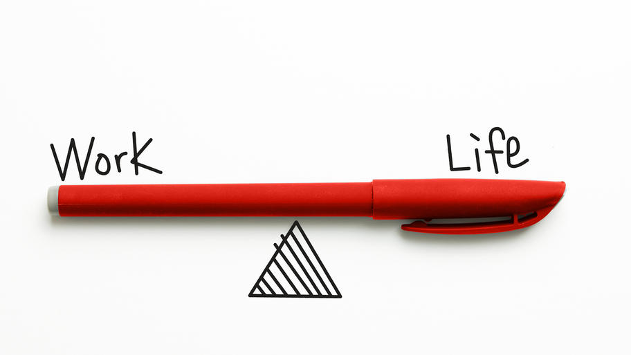 Red pen balancing on triangle with the words "work" and "life."