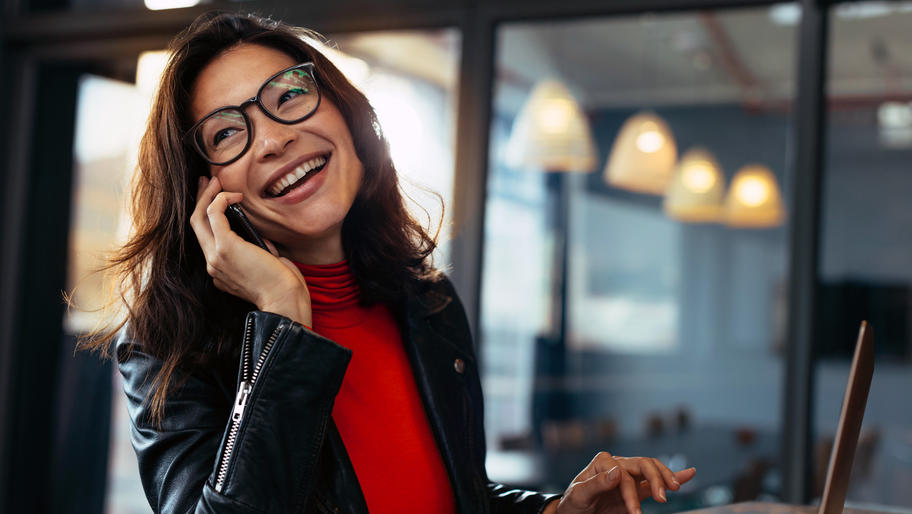 Woman at work wearing glasses and smiling as she talks on phone