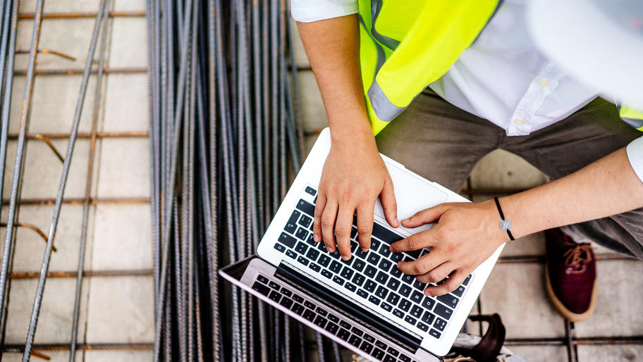 Man wearing reflective vest with his hands on laptop keyboard