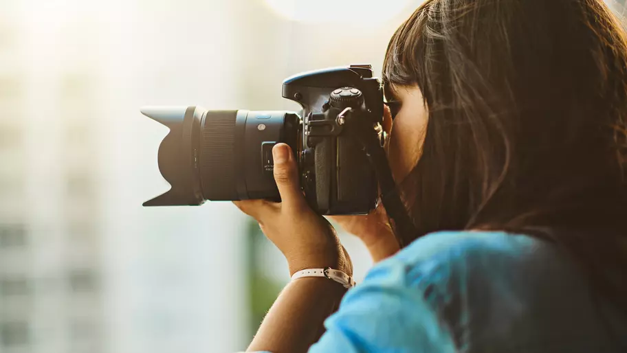 Close up of young female photographer holding camera to her face.