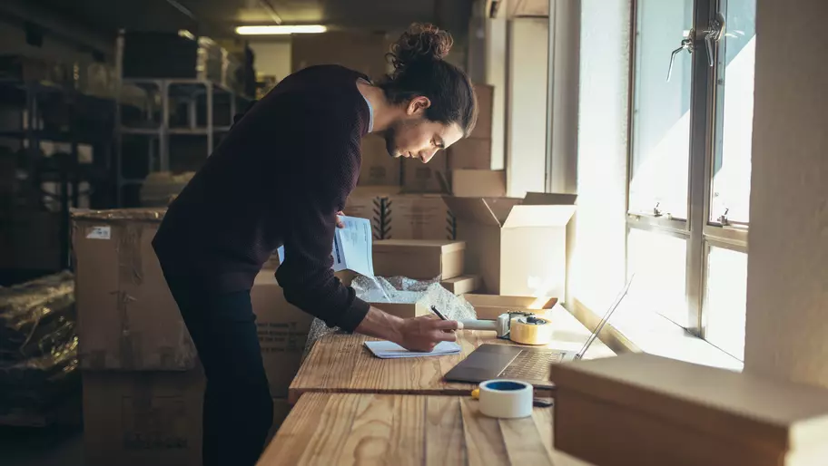 Young man standing over work bench with laptop. Side hustle to small business.