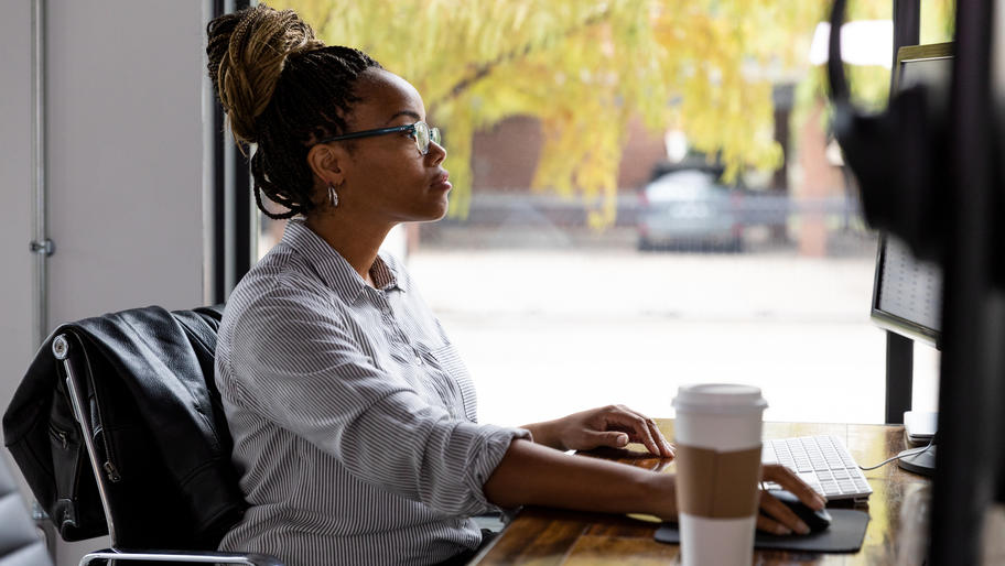 Black business owner sitting at computer with coffee.