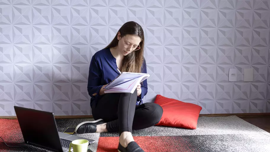 Femle neurodiverse business owner sitting on red, black, and white floor with computer