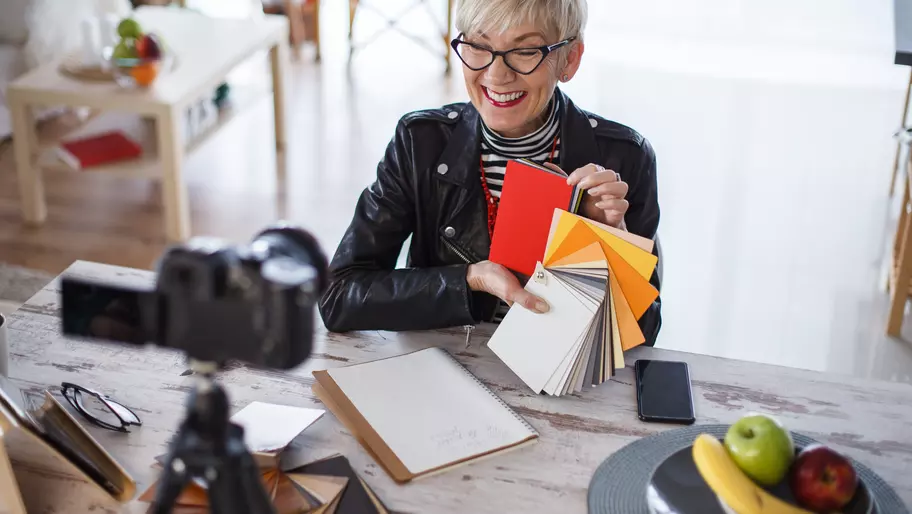 Charming female small business owner showing color swatches to camera while filming a video