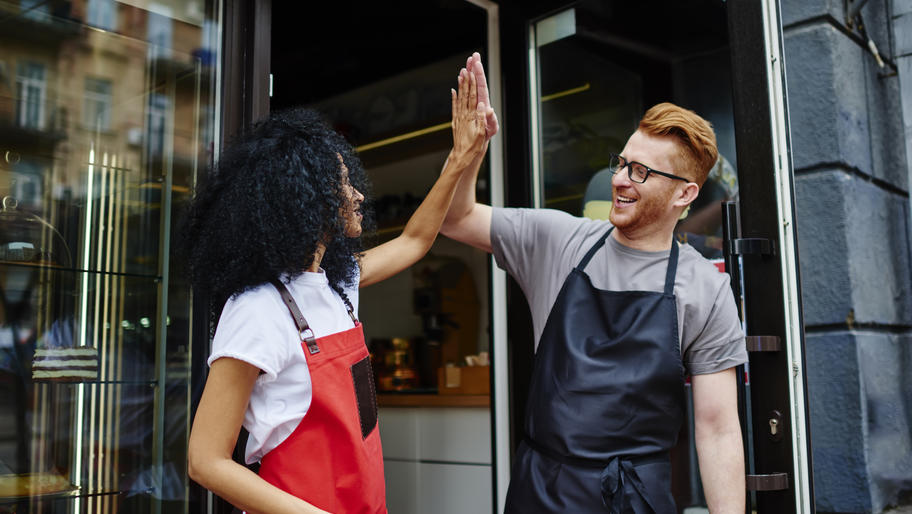 male and femle business owners giving a high-five outside storefront