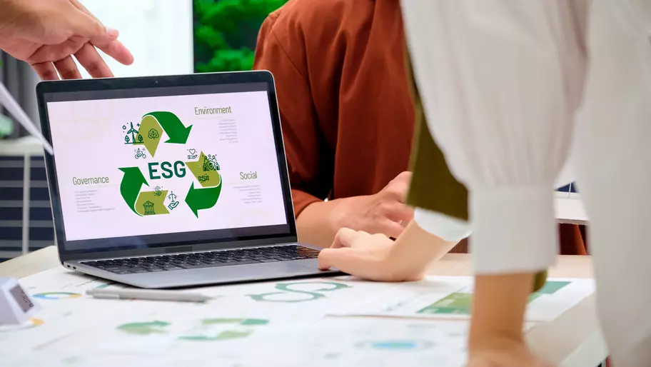 employees sitting around a laptop with environmental symbols to use in effective green marketing