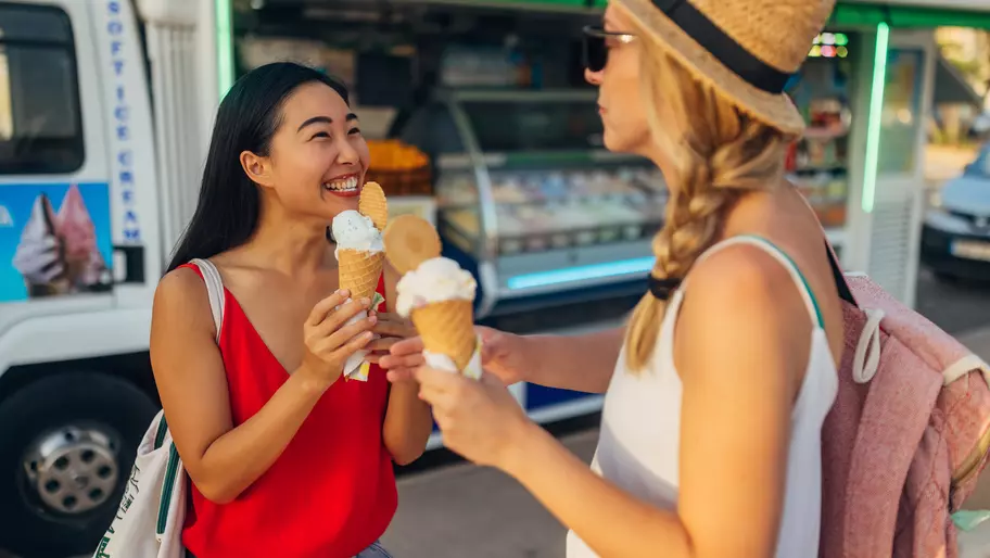 two females eating ice cream in front of a seasonal small business ice cream truck