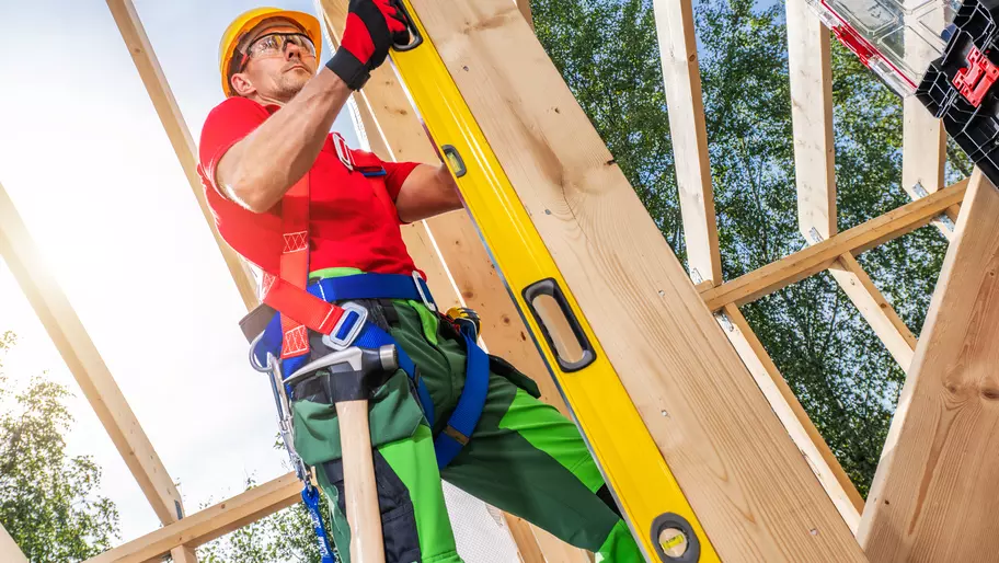 contractor in red shirt working on job site constructing building frame