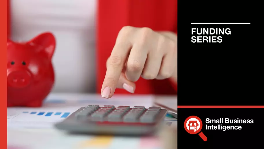 small red piggy bank on the left, hand pressing keys on a calculator figuring out SBA loans for business
