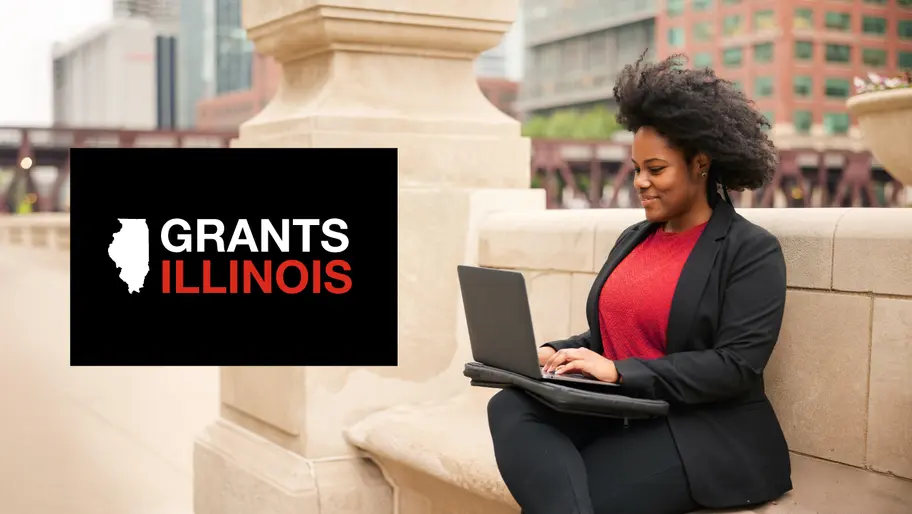 Black businesswoman outside using a laptop researching grants in Illinois