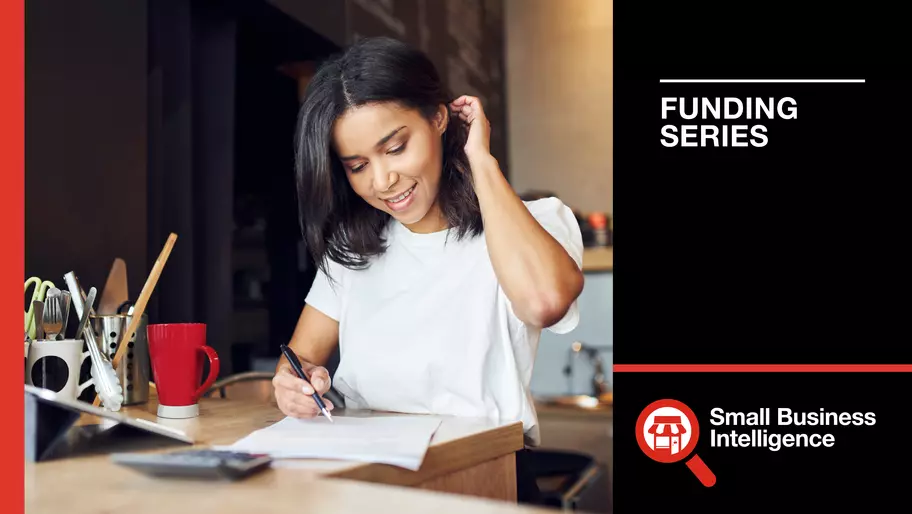 Businesswoman in white blouse fixing her hair while investigating merchant cash advances for her business.