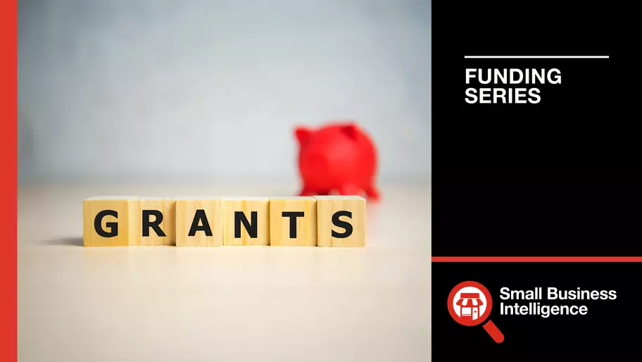Wooden blocks spelling out GRANTS leading up to a small red piggy bank