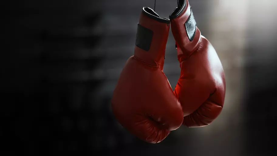 Red boxing gloves dangling over ring. A tribute to the legacy left behind by George Foreman