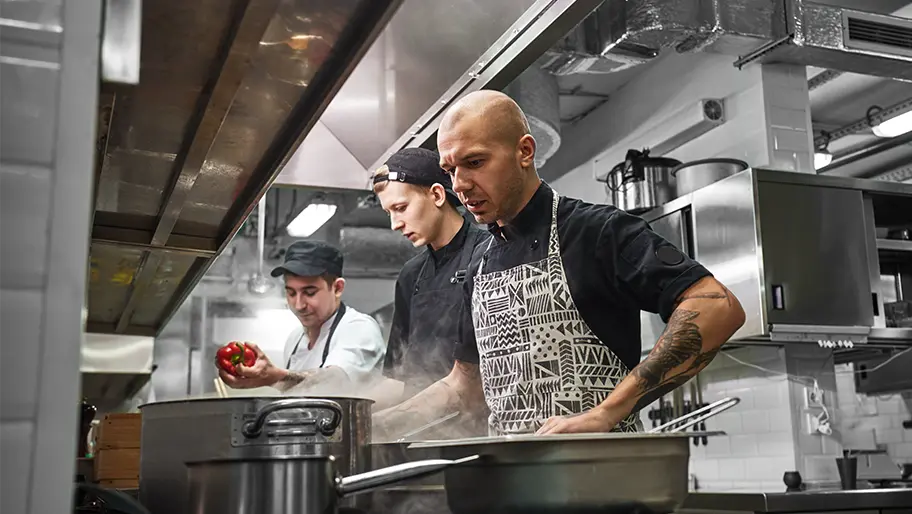 three male chefs at stove in commercial kitchen, similar to one on The Bear