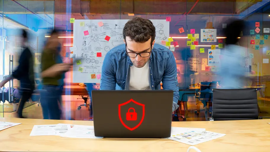 Small business owner working on a laptop with a digital security lock icon, representing cyber hygiene and data protection