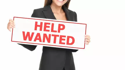 Woman holding a Help Wanted sign