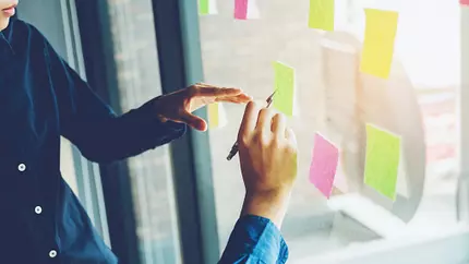 People writing on sticky notes and sticking them to window