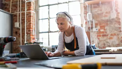 Older woman in workshop looking at laptop screen