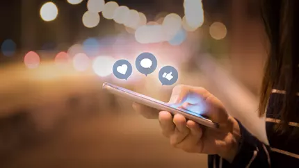 Hand holding smart phone and social media icons.