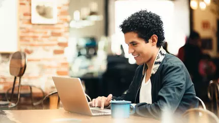 Young adult male on laptop in public place