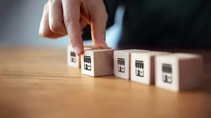 Man's hand on wooden block with image of a storefront on it.