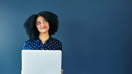 Woman standing in front of blue background holding laptop. Social media for businesses.