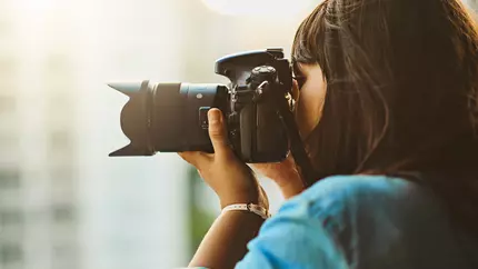 Close up of young female photographer holding camera to her face.