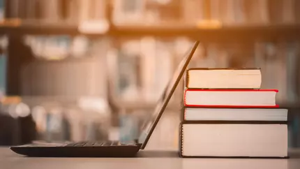 Cyber security IQ. Laptop propped up against library books.