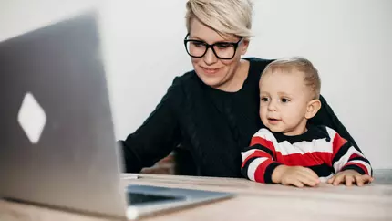 mom entrepreneur sitting at computer, working with her young child on her lap