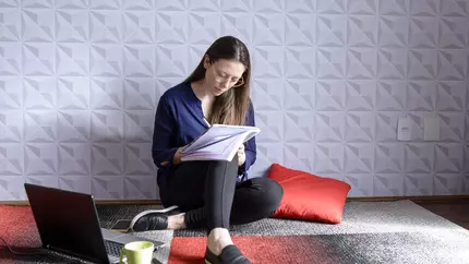 Femle neurodiverse business owner sitting on red, black, and white floor with computer
