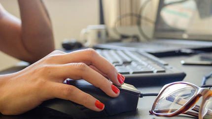 hand of a small business woman using a computer mouse at her desk