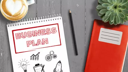 creating a business plan notebook on desk with coffee
