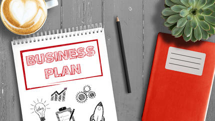 creating a business plan notebook on desk with coffee