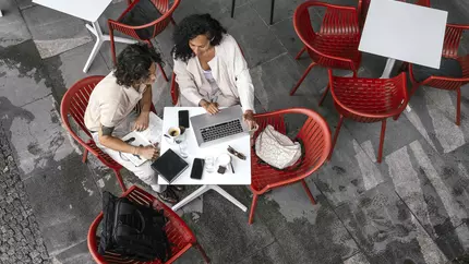 Female executive coach assisting a client while sitting in red chairs in a business casual setting.