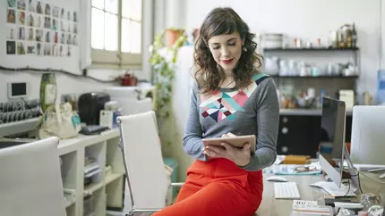 Female business owner in office using her tablet to get plans in place and set goals for Q2