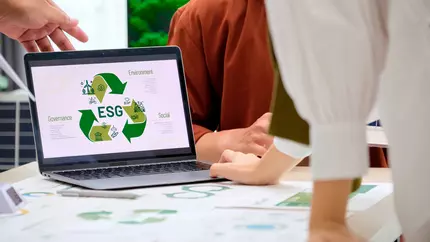 employees sitting around a laptop with environmental symbols to use in effective green marketing