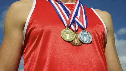 athlete in red sleeveless shirt decorated with gold, silver, and bronze medals