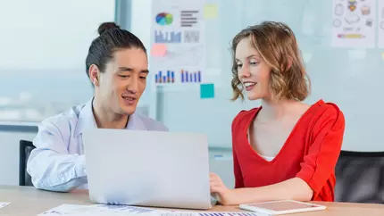 Smiling business consultants discussing liability coverage over laptop in office
