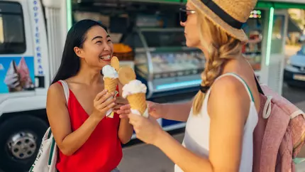 two females eating ice cream in front of a seasonal small business ice cream truck