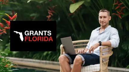 Business owner in casual clothing sitting outside surrounded by plants using laptop to search top grants in Florida
